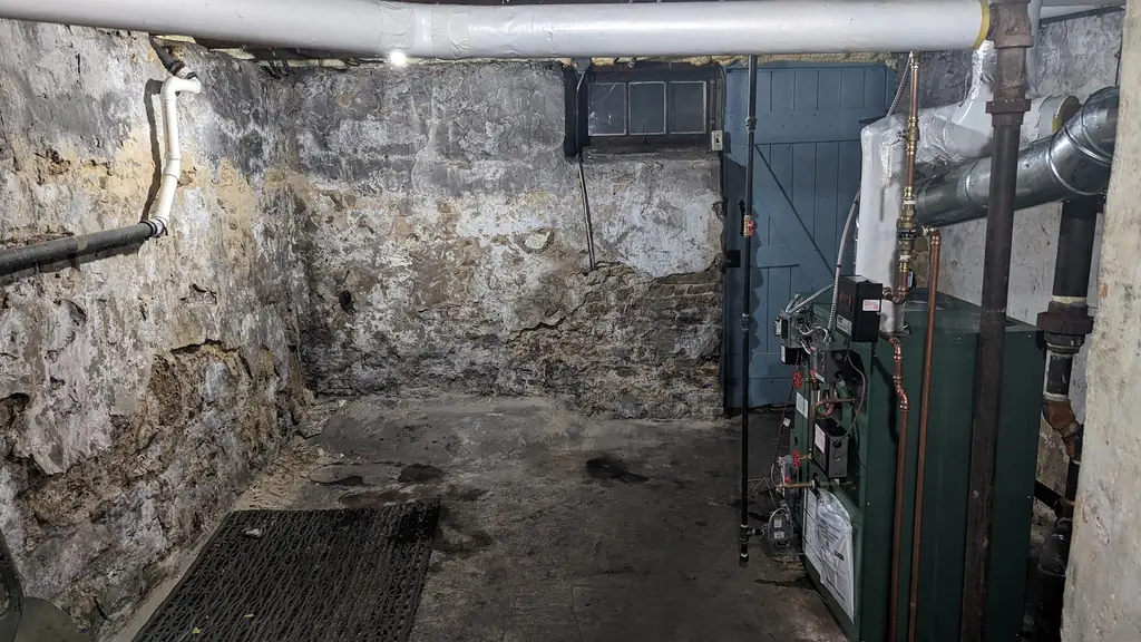 The same stone basement after the oil tank was removed, with the new green boiler installed in the corner