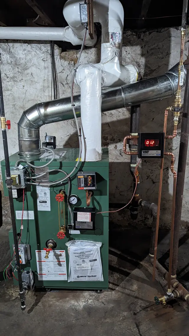 Finished boiler installation with a new metal flue, insulated piping, copper manifold and a digital water feeder